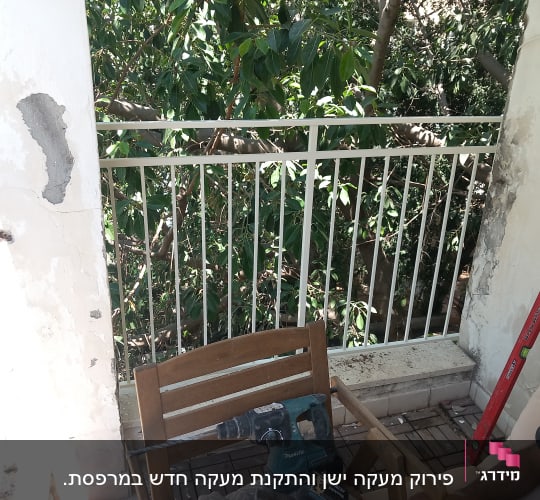 מעקה מתכת לבן עם עצים ברקע, מקדחה ומד זווית אדום